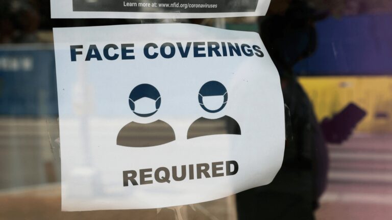 A visitor wearing a mask to protect against the spread of COVID-19 passes a sign requiring masks, Tuesday, July 7, 2020, in San Antonio. Texas Gov. Greg Abbott has declared masks or face coverings must be worn in public across most of the state as local officials across the state say their hospitals are becoming increasingly stretched and are in danger of becoming overrun as cases of the coronavirus surge. (AP Photo/Eric Gay)